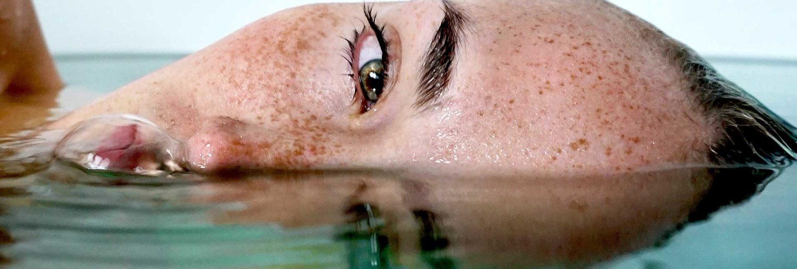 a woman's freckled face half in and half out of water
