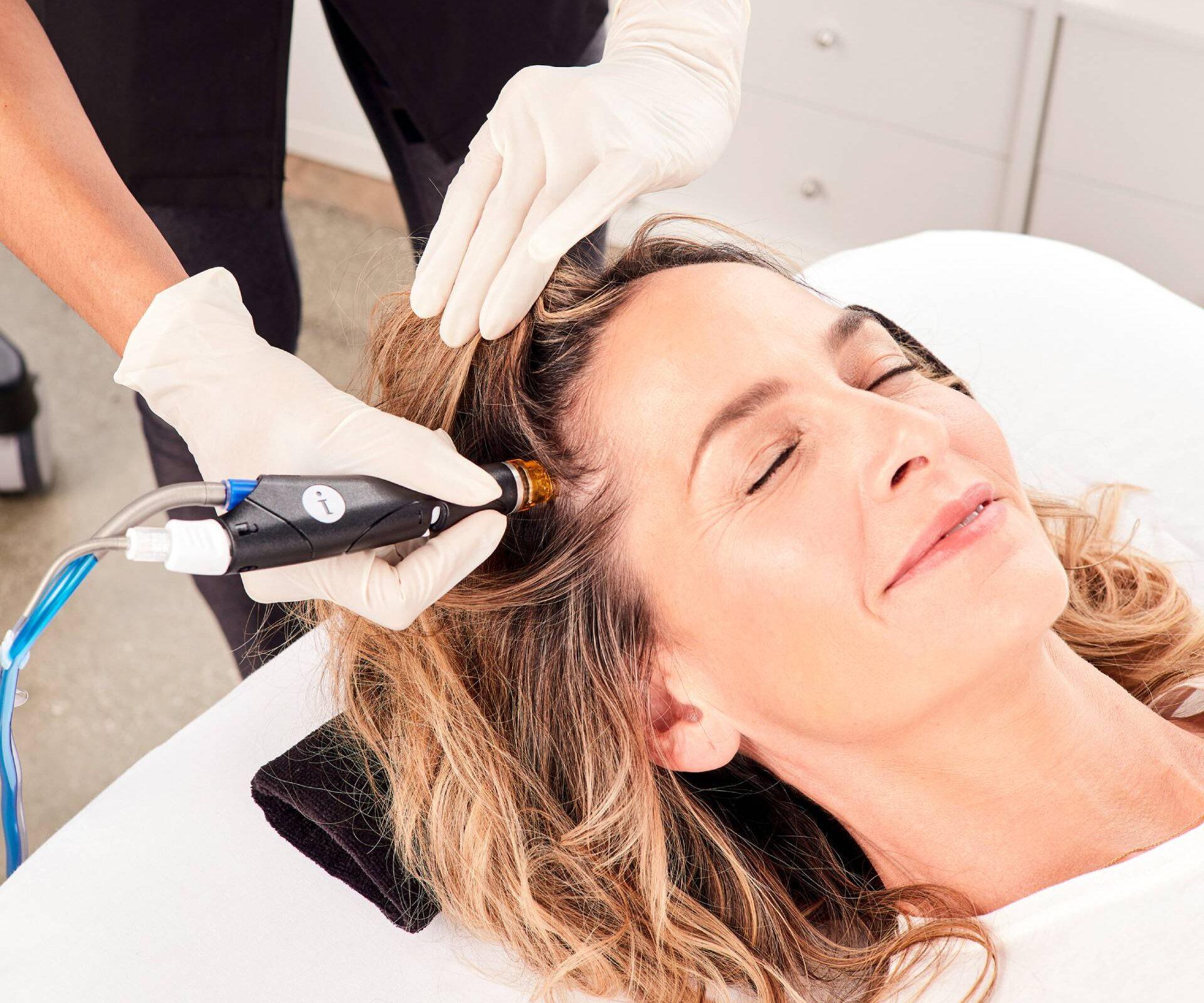 a woman receiving scalp treatment at a spa